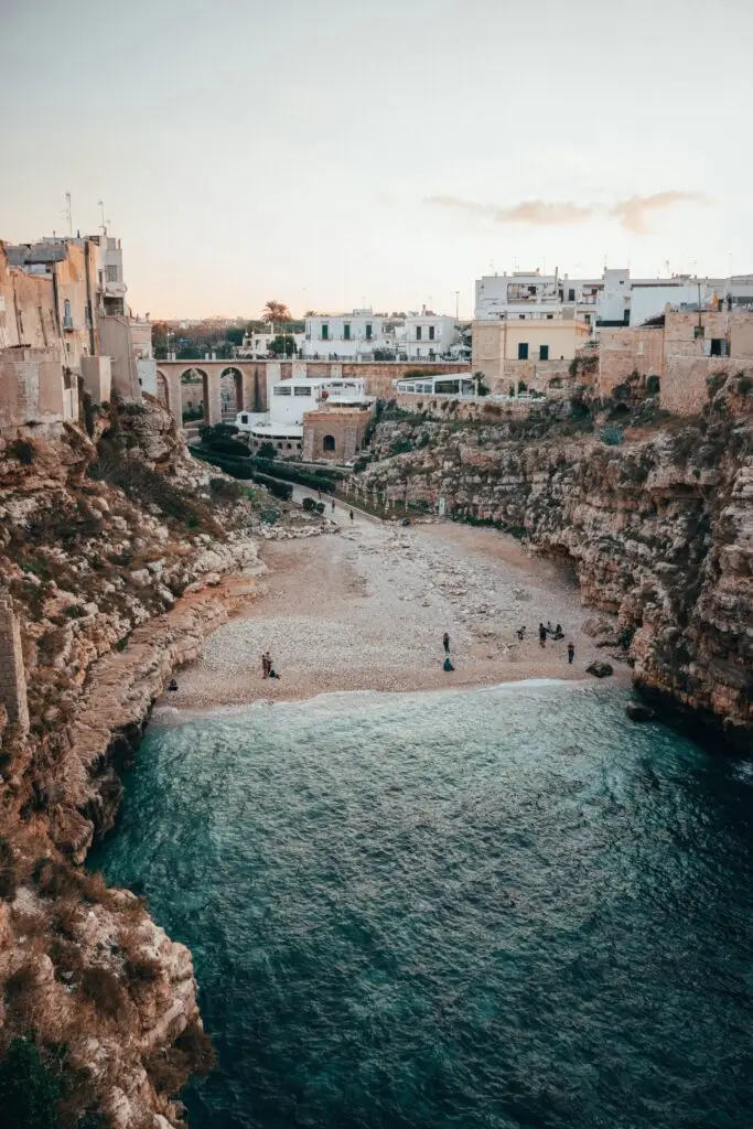 Breathtaking view of Polignano a Mare's rocky cliffs and serene beach, perfect for summer vacations.