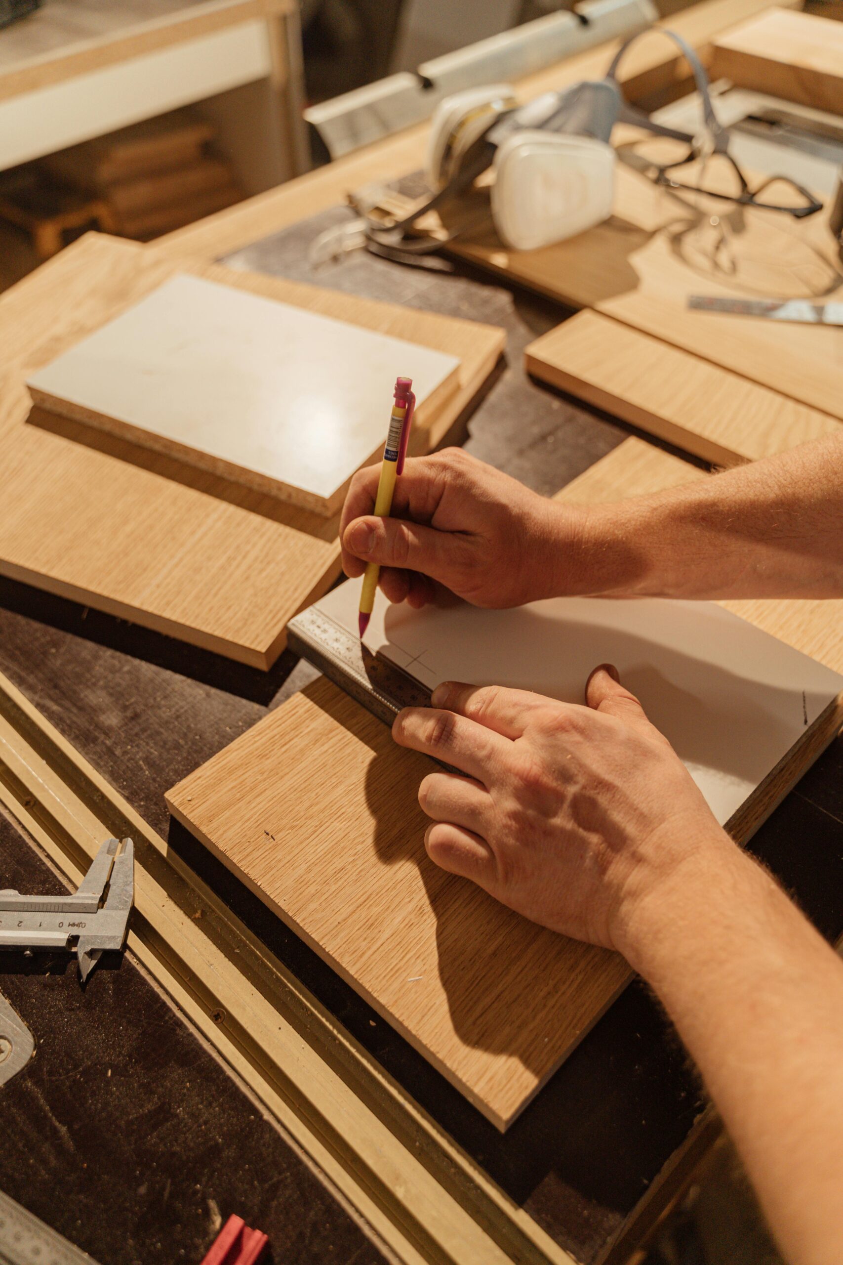 A skilled woodworker measuring wood pieces in an indoor workshop.