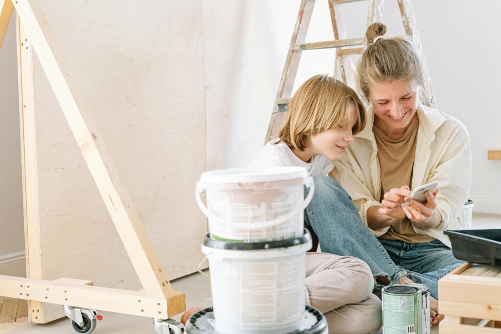 Mother and son smile while looking at a smartphone during a home renovation project.