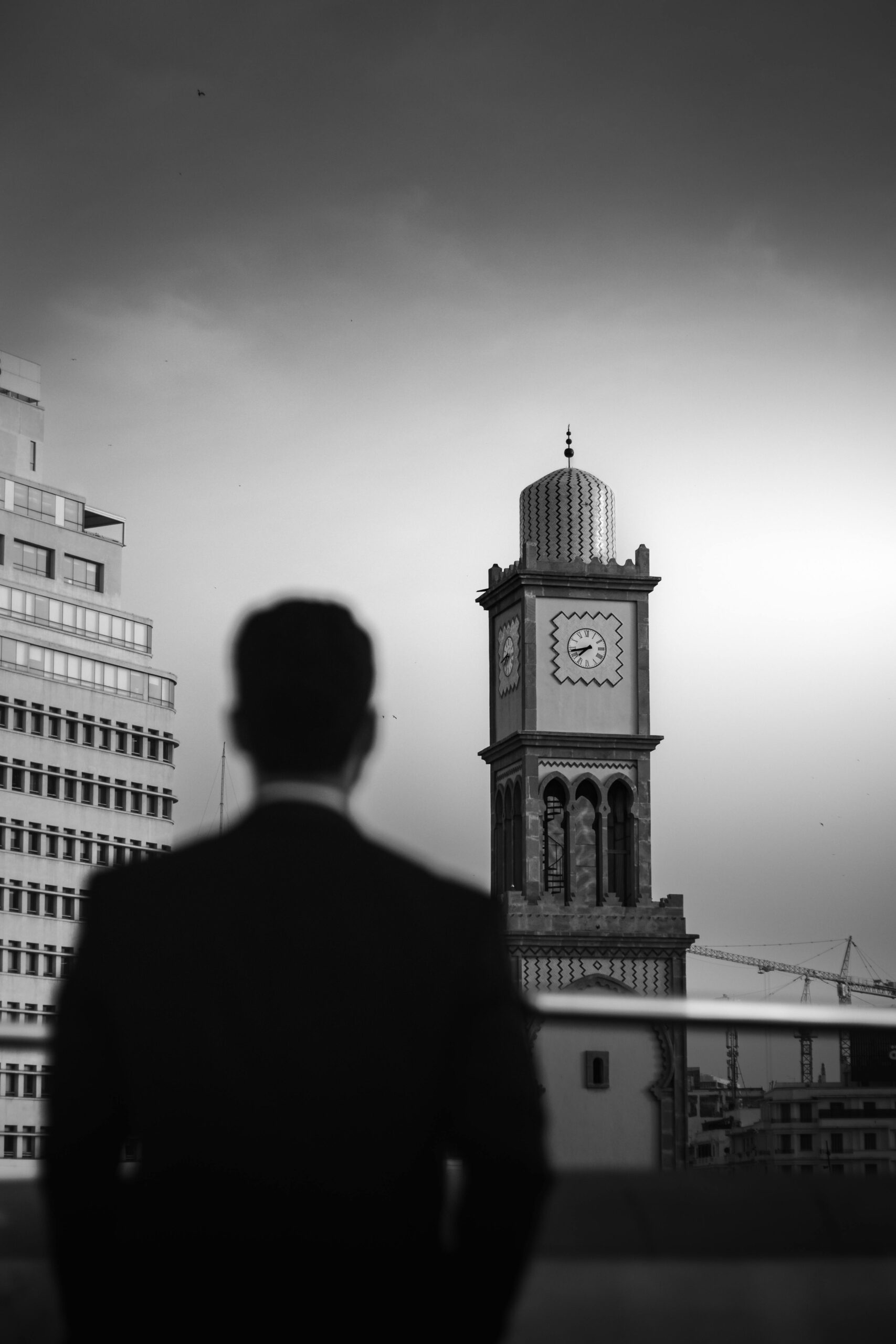 Black and white image of a man in a suit overlooking the iconic clock tower in Casablanca, Morocco.